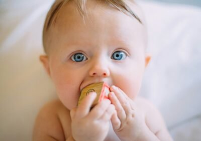 selective focus photography of baby holding wooden cube